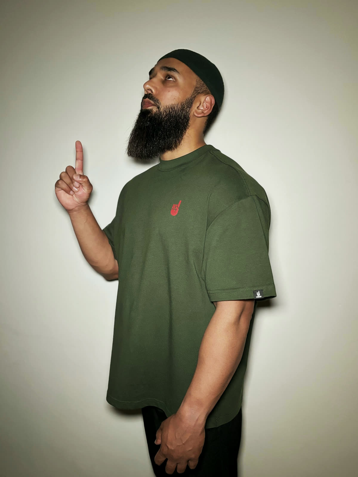 The Reminder Tee in olive, worn with one finger raised